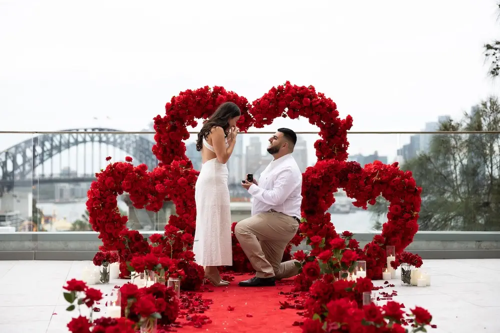 couple proposing with a red floral heart background